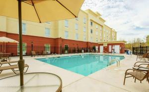 奥古斯塔Hampton Inn by Hilton Augusta Fort Eisenhower的酒店游泳池设有椅子和遮阳伞