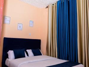 EmbuModern & Homely Suite with Free Parking & WiFi的一间卧室设有两张床和蓝色窗帘