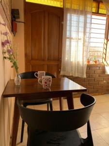 戈多伊克鲁斯Departamento Privado para dos personas en Mendoza的一张木桌,上面有两个杯子和花瓶