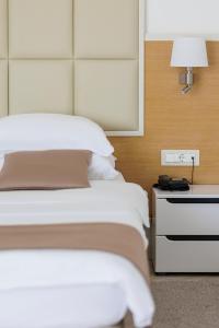 布德瓦Hotel Kadmo by Aycon的一间卧室配有一张床和一个带灯的床头柜