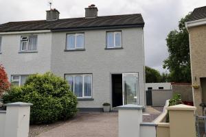 基洛格林Centrally located house on Ring of Kerry的灰色的房子,有白色的窗户和车道