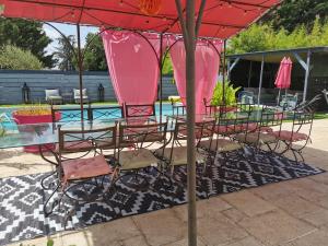 Roézé-sur-SartheChambre double dans villa avec piscine salle de bains privée的红色伞下的桌椅