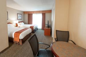 坎贝尔河安佳套房旅馆的酒店客房带两张床和一张桌子以及椅子。