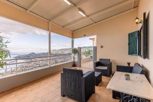 丰沙尔Villa das Furnas的一间带桌椅的客厅和一个阳台