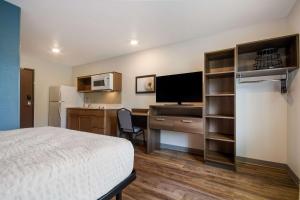 巴拿马城海滩WoodSpring Suites Panama City Beach的酒店客房配有一张床和一张书桌及一台电视