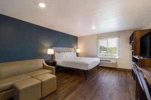巴拿马城海滩WoodSpring Suites Panama City Beach的一间卧室配有一张床、一张沙发和一台电视