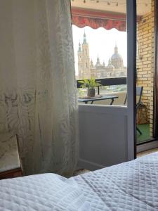 萨拉戈萨Apartamento Con Vistas Al Pilar con Aparcamiento privado的一间卧室设有一张床和一个美景窗户。