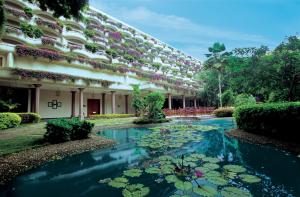 班加罗尔班加罗尔欧贝罗伊酒店&度假村的一座建筑,前面有一个养着百合花的池塘