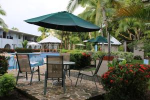 奎波斯城Tropical Bliss Pool Wi-Fi BBQ Near Quepos Manuel Antonio的游泳池旁配有遮阳伞的桌椅