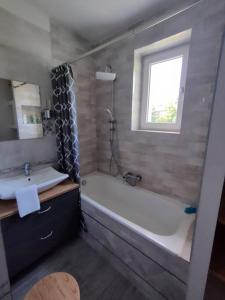 斯图托沃Brook-Stone Beach Guesthouse的带浴缸、水槽和窗户的浴室