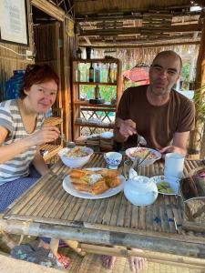 Phumĭ Ândong PringBattambang Eco Stay的坐在餐桌旁吃饭的男人和女人