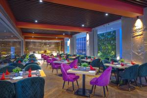 阿格拉Royale Sarovar Portico Agra的一间用餐室,配有紫色的椅子和桌子