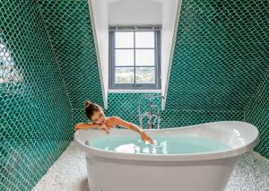 下龙湾Grand Fleuve Boutique的绿色瓷砖浴室里的一个女孩浴缸里