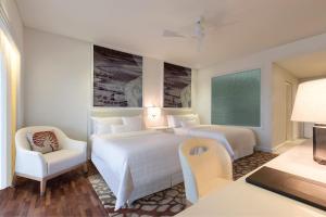 瓜埠 兰卡威威斯汀水疗度假村的酒店客房 - 带两张床、一张桌子和一把椅子