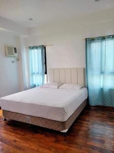 麦克坦Lux 7 Pool Villa Mactan的卧室内的一张床铺,配有蓝色窗帘和木地板
