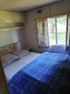 乌斯马坎普宁梅马拉斯露营地的一间卧室配有一张带蓝色棉被的床和窗户。