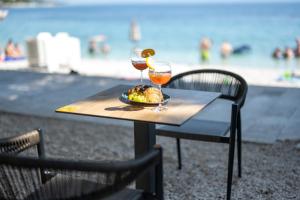 布雷拉Aurora Beachfront Luxury Rooms&Suites的一张桌子,上面放着一盘食物和两杯葡萄酒