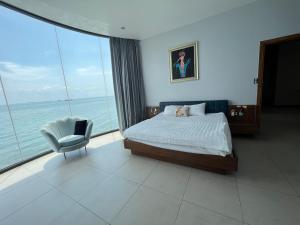 头顿Nancy Grand Vung Tau Villa的一间带一张床和一把椅子的卧室,享有海景