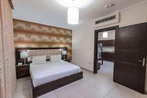 安曼兰开斯特公寓花园酒店的卧室设有一张白色大床和一个走廊