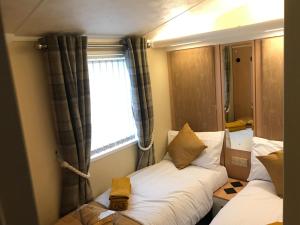 拉尔Hot Tub Accommodation North Wales Caravan的小房间设有两张床和窗户