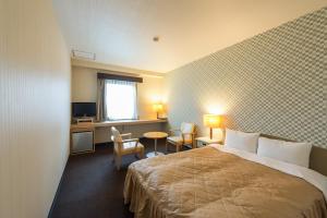 甲斐市HOTEL LiVEMAX Kofu的酒店客房带一张床、一张桌子和椅子