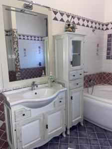 兰佩杜萨VILLA HELENA的一间带水槽、浴缸和镜子的浴室