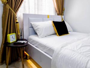 阿布贾Cozy Apartment - Hideaway with 5G WiFi的一张白色的床,上面有黑色和黄色的枕头