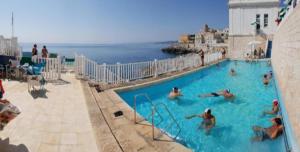 圣凯撒利亚温泉Residence Porto Miggiano的一群人在靠近海洋的游泳池里