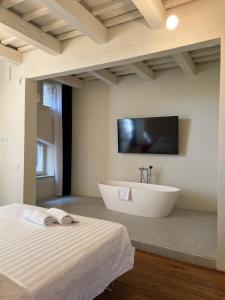 乌尔比诺Urbino Apartment - Torricini View的带浴缸的大浴室和墙上的电视