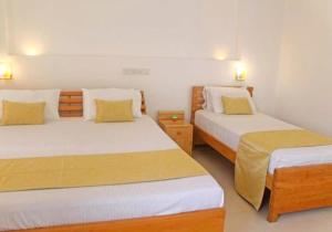 NawalaApna Colombo的一间卧室配有两张带黄色枕头的床