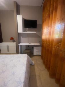 兰佩杜萨VILLA HELENA的一间卧室配有一张床、一张书桌和一台电视