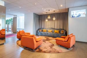 安特卫普安特卫普皇冠假日酒店的客厅配有橙色椅子和沙发