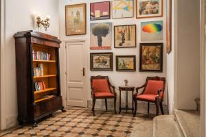 锡切斯梅迪姆浪漫酒店的走廊上设有两把椅子、书架和绘画作品