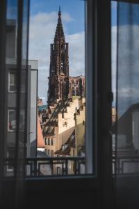 斯特拉斯堡Maison Rouge Strasbourg Hotel & Spa, Autograph Collection的从带钟楼建筑的窗户欣赏美景