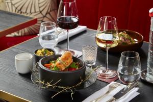 斯特拉斯堡Maison Rouge Strasbourg Hotel & Spa, Autograph Collection的餐桌,放着一碗食物和酒杯