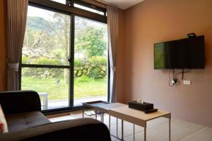 竹山山林别苑的客厅配有沙发和墙上的电视