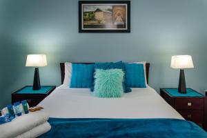 麦克拉伦谷McLaren Vale Studio Apartments的一间卧室配有一张带蓝色枕头的床和两盏灯。