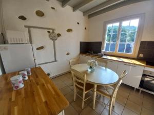 AdéMaison de vacances的厨房配有桌子、桌子和冰箱。