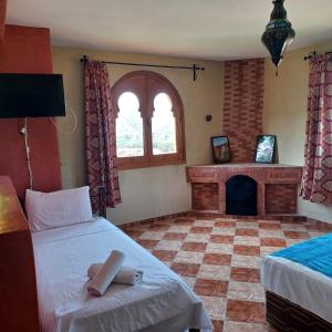 OuzoudMaison d´hôtes Amazir的一间卧室设有两张床和一个壁炉