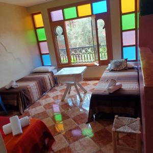 OuzoudMaison d´hôtes Amazir的带三张床和彩色玻璃窗的客房
