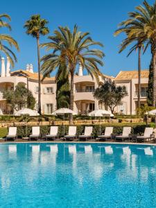 卡武埃鲁Vale d'Oliveiras Quinta Resort & Spa的一座建筑前的游泳池,里面设有椅子和棕榈树