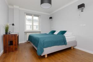 华沙City Center Aparthotel Chmielna by Renters的白色卧室配有一张带蓝色毯子的床