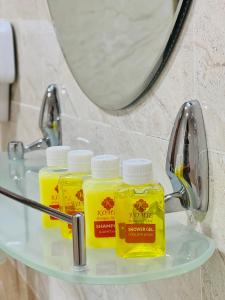布哈拉考米尔精品酒店的三个黄液体坐在浴室的架子上