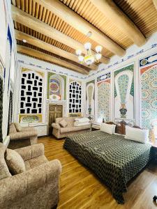 布哈拉考米尔精品酒店的客房设有一张床和一张沙发,墙上挂有绘画作品