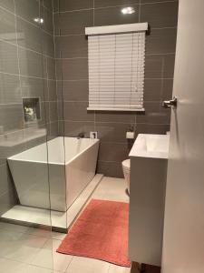 布莱克敦Charming & Cozy 2BR Cottage的带浴缸、盥洗盆和卫生间的浴室