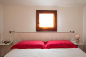 奥尔比亚Casa Olbiamare by Wonderful Italy的一间卧室配有一张带红色枕头的床和一扇窗户