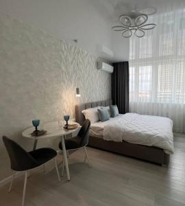 基辅Deluxe apartments - Viva Ukraine的卧室配有一张床和一张桌子及椅子