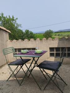 叙兹拉鲁斯Studio calme dans les vignes的一张桌子、两把椅子和一张带盘子和碗的紫色桌子