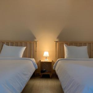春川Hostel Espace的床头柜上灯的两张床
