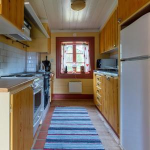 SollerönTraditionell Timmerstuga - Mora, Gesunda的厨房配有木制橱柜和地板上的地毯。
